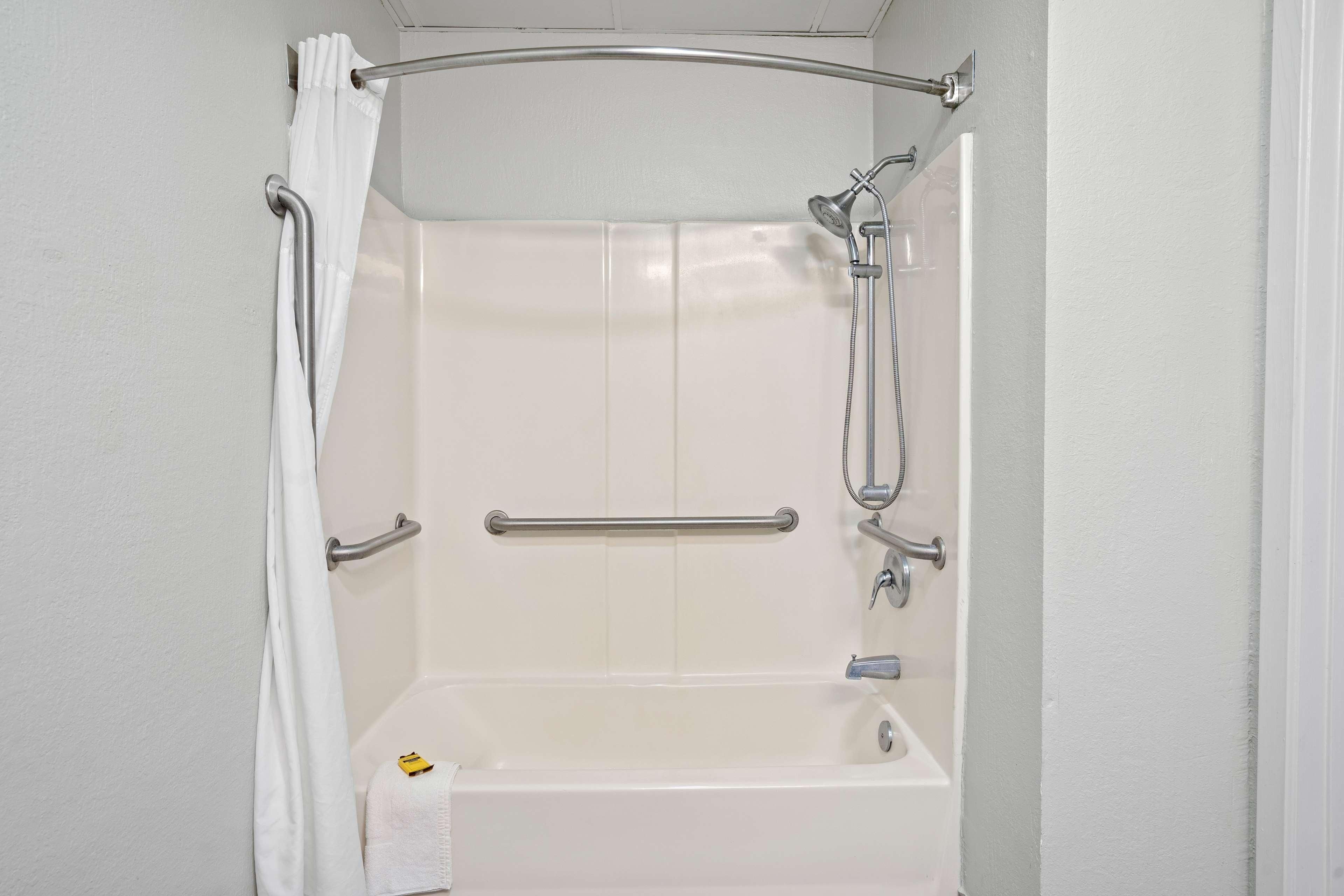 Een witte douche met een handgreep, een flexibele douchekop en een handdoekhouder.