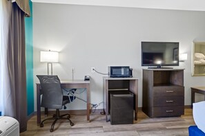 A hotel room with a desk, chair, microwave, television, and a small refrigerator. - Blue Water Inn & Suites, Bw Signature Collection (Sneads Ferry)