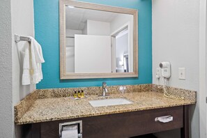 A bathroom with a granite countertop, a sink, a mirror, a towel rack, and a hairdryer. - Blue Water Inn & Suites, Bw Signature Collection (Sneads Ferry)