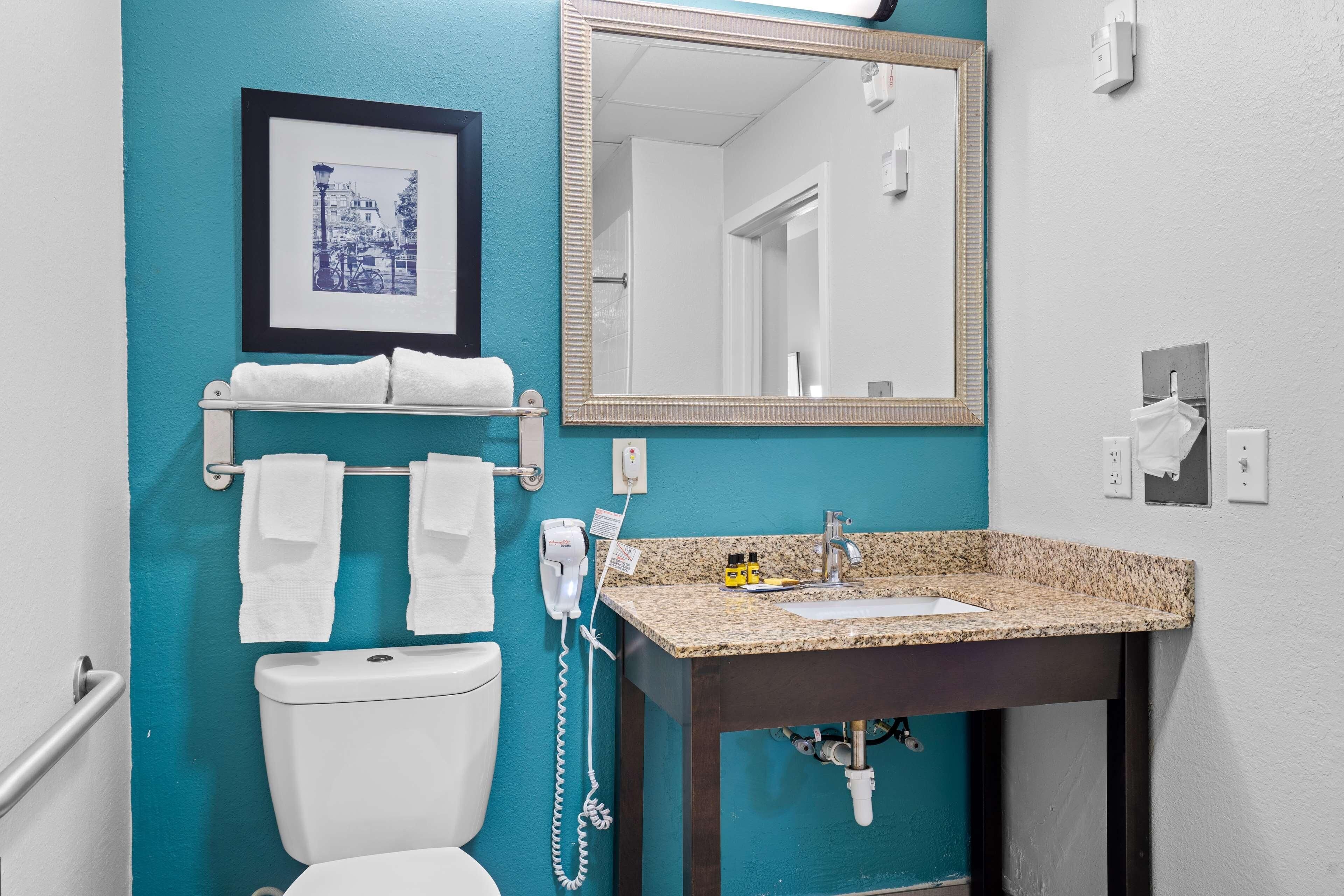 A bathroom with a toilet, sink, towel rack, and a framed picture on the wall.