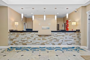 Zona de recepción con pared de piedra, mostrador y suelo con diseño azulado.
