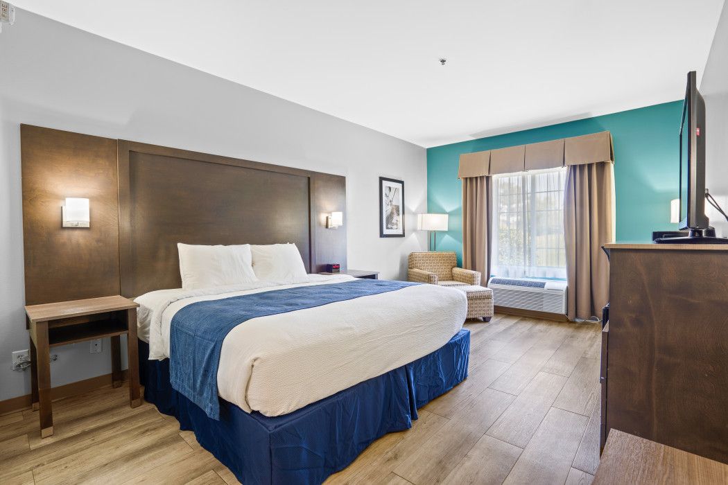 Ein Hotelzimmer mit Bett, Nachttisch, Sessel und Fernseher.