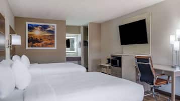 A hotel room with a large bed, a desk with a chair, a flat-screen TV, and a painting on the wall.
