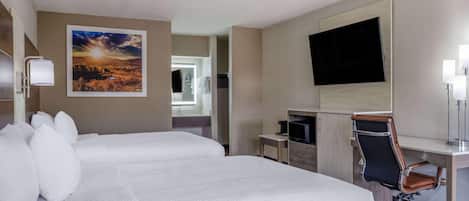 A hotel room with a bed, a desk with a chair, a flat-screen TV, and a painting on the wall.