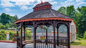 A gazebo with a tiled roof, wooden pillars, and a fenced area with hanging flower baskets. - Days Inn by Wyndham Clemson (Clemson)