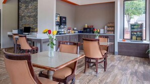 A modern kitchen with a stone backsplash, a flat-screen TV, and a coffee machine. - Days Inn by Wyndham Clemson (Clemson)