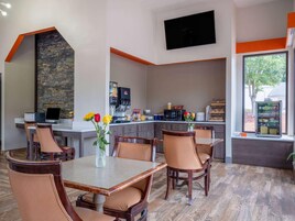 Una cocina moderna con salpicadero de piedra, un televisor de pantalla plana y una cafetera.