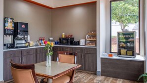 A small kitchenette with a coffee machine, microwave, and a window with a view of trees. - Days Inn by Wyndham Clemson (Clemson)