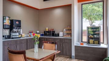 A small kitchenette with a coffee machine, microwave, and a window with a view of trees.