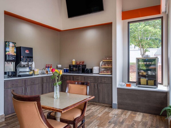A small kitchenette with a coffee machine, microwave, and a window with a view of trees. - Days Inn by Wyndham Clemson (Clemson)