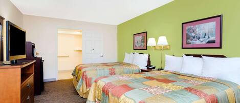 A hotel room with two beds, a television, a dresser, and two framed pictures on the wall.