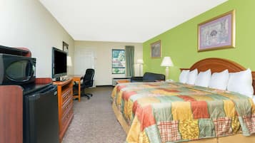A hotel room with a bed, desk, television, and a window with curtains.