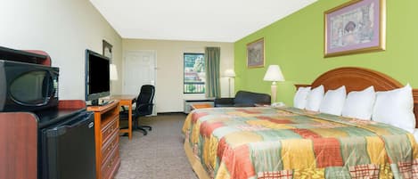 A hotel room with a bed, desk, television, and a window with curtains.