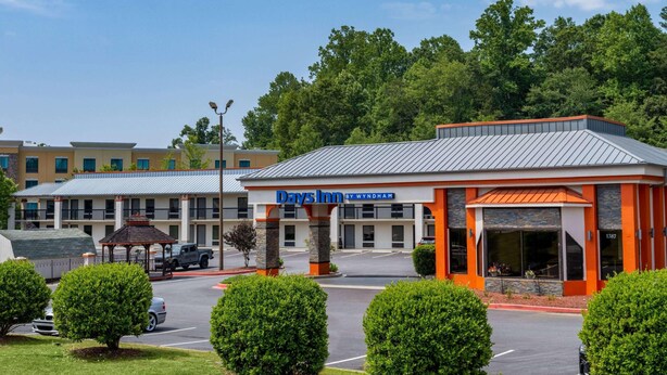 A Days Inn by Wyndham with a parking lot, a gazebo, and a building with orange and grey architecture. - Days Inn by Wyndham Clemson (Clemson)
