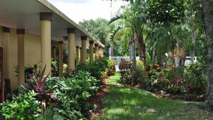 A covered outdoor area with columns, a pathway, and various plants. - Ramada by Wyndham Cocoa (Cocoa)