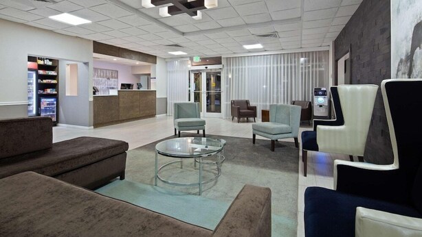 A modern lobby with seating areas, a reception desk, and a vending machine. - Ramada by Wyndham Cocoa (Cocoa)