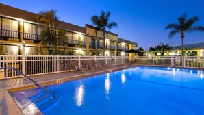 A hotel with a swimming pool, white fences, and palm trees. - Ramada by Wyndham Cocoa (Cocoa)
