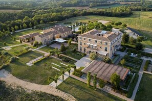 Vista aérea de una extensa propiedad con varias construcciones, jardines amplios y un césped bien cuidado.