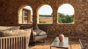 Ein Zimmer mit Steinwänden, einer Couch und einem Tisch, ein Fenster mit Blick auf die Landschaft.