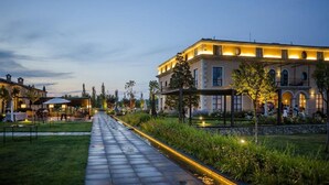 Un hotel amb un passeig pavimentat, zones d'estar a l'aire lliure i una façana ben il·luminada.