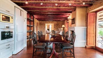 Ein Esszimmer mit einem großen Holztisch, Stühlen und einer Steinwand im Hintergrund.