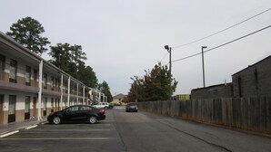 Een straat met een rij motelachtige gebouwen, een houten omheining en geparkeerde auto's.