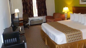 Une chambre d’hôtel équipée d’un lit, d’un bureau, d’une chaise, d’un climatiseur et d’une lampe.