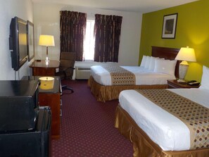 Une chambre d’hôtel avec deux lits, un bureau, une chaise, une télévision et une lampe.