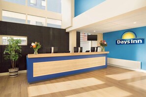 Una recepción con diseño azul y de madera, un cartel de 'Days Inn' y una planta a la izquierda.