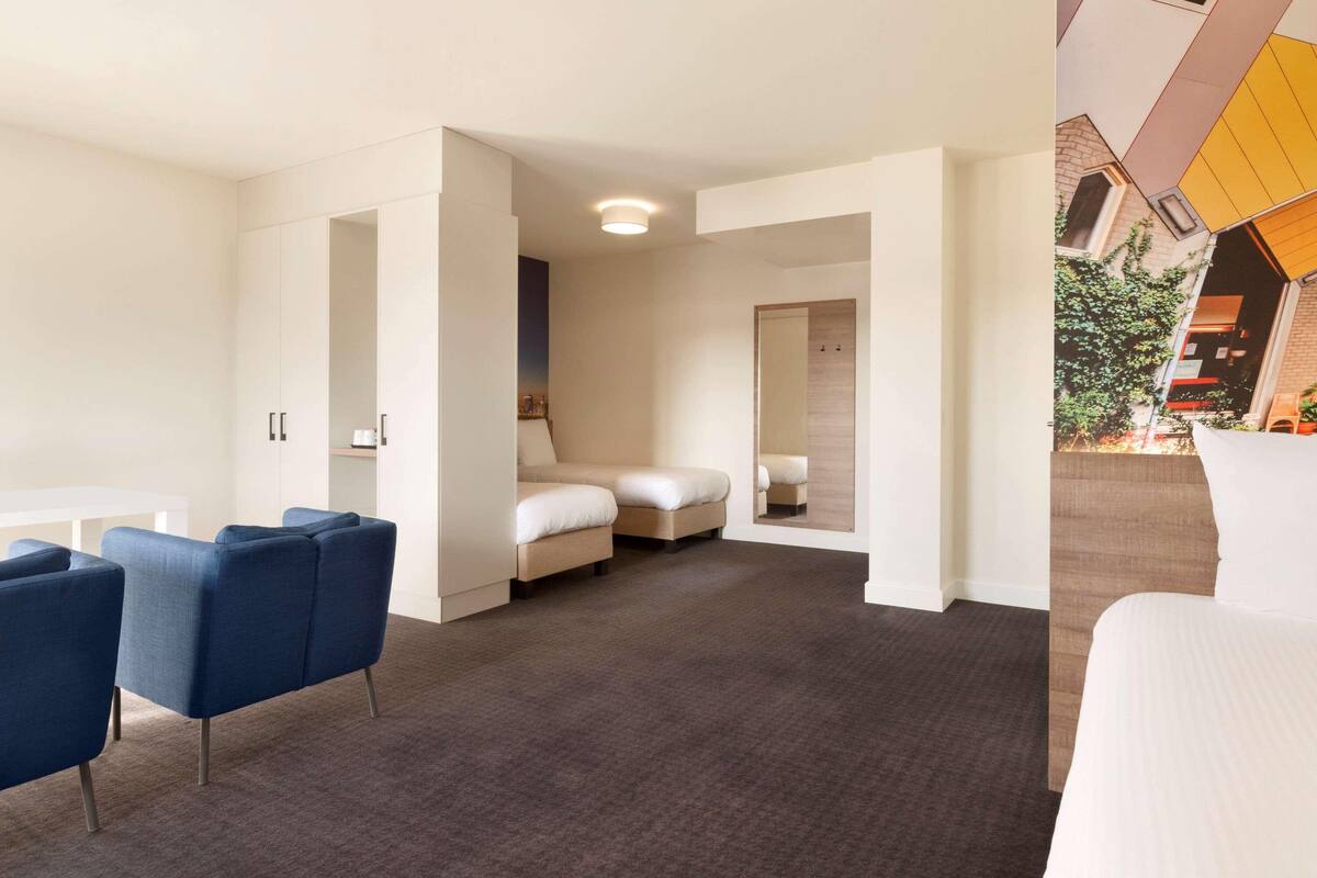 A modern hotel room with a sofa, a bed, and a small table.