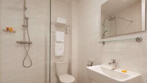 A bathroom with a shower, toilet, sink, and a mirror. - Rotterdam Teleport Hotel (Rotterdam)