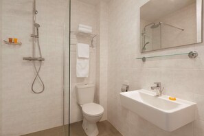 Un baño con ducha, inodoro, lavabo y espejo.