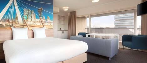 A hotel room with a large bed, a sofa, a TV, and a cityscape view.