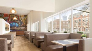A restaurant with booths, a mural, and a view of buildings. - Rotterdam Teleport Hotel (Rotterdam)