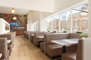 Un restaurante con cabinas, un mural y vistas de edificios.