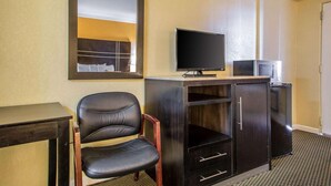 A hotel room with a large mirror, a flat-screen TV, a small refrigerator, a desk, and a leather chair. - The Boards AC (Atlantic City)