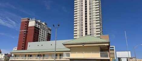 A hotel with a parking lot, a tall building in the background, and a clear blue sky.