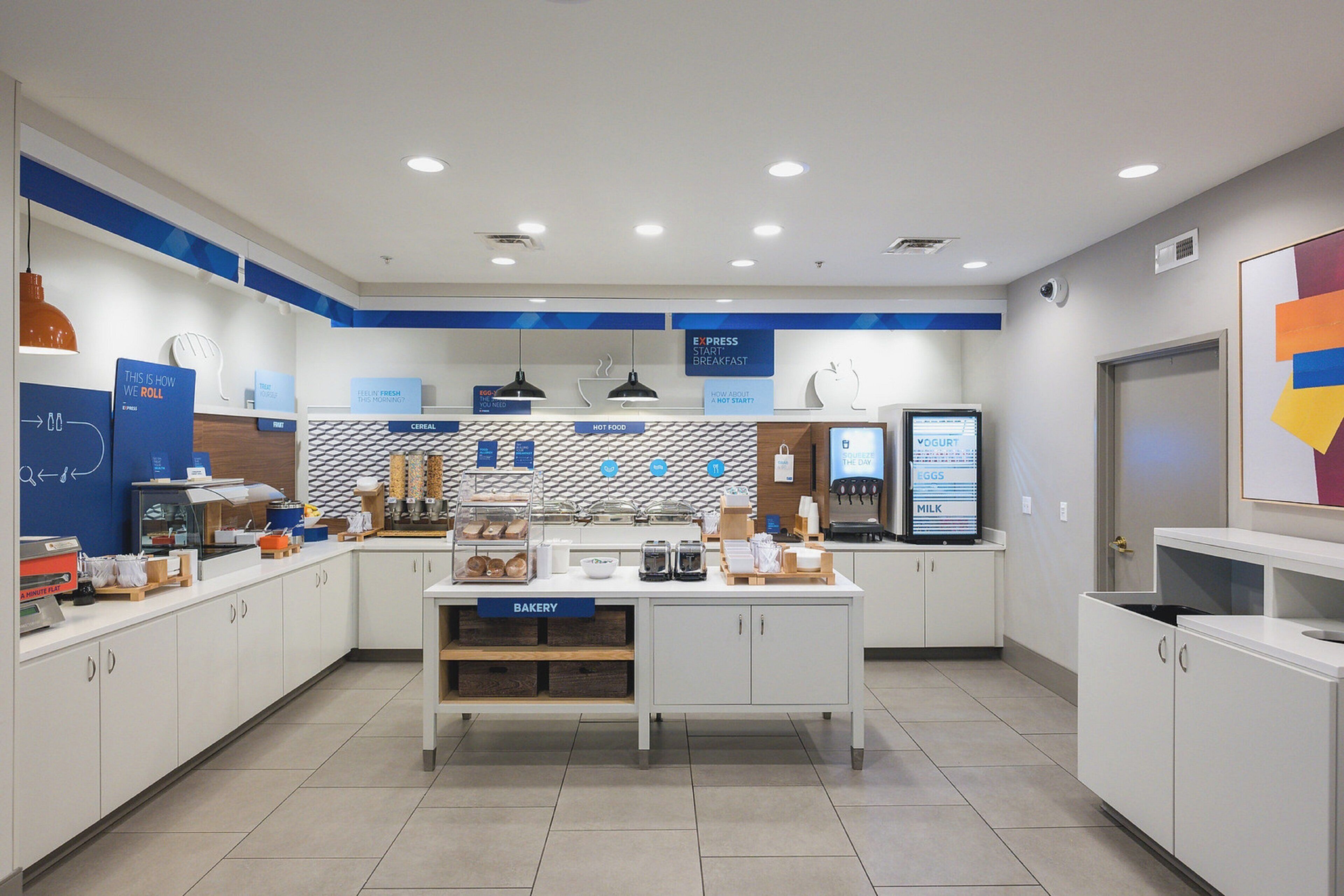 Un espace moderne dédié au petit-déjeuner, comprenant un coin boulangerie, un espace pour préparer le café et un présentoir à yaourts.