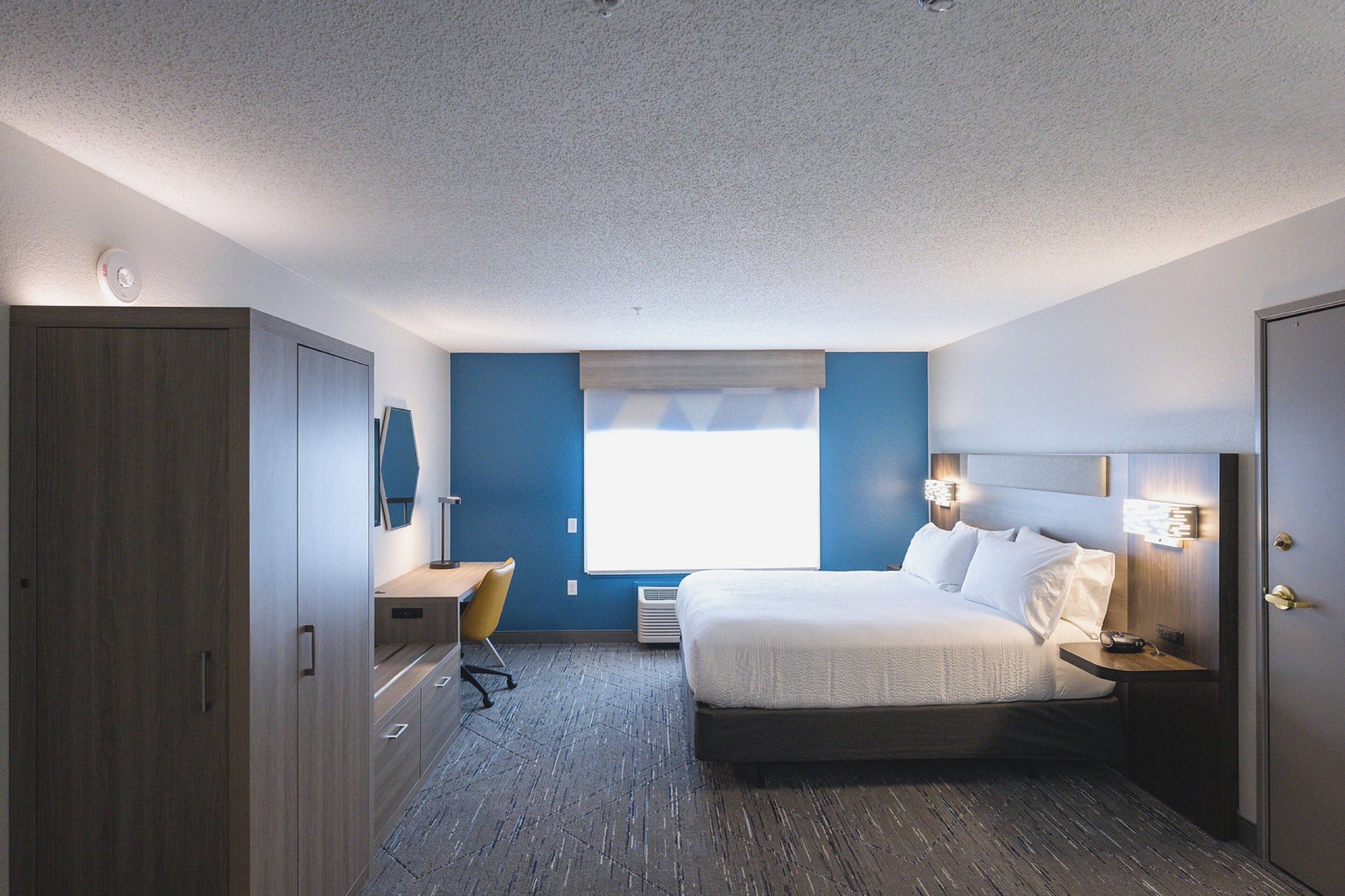 Een hotelkamer met een bed, bureau en kledingkast.