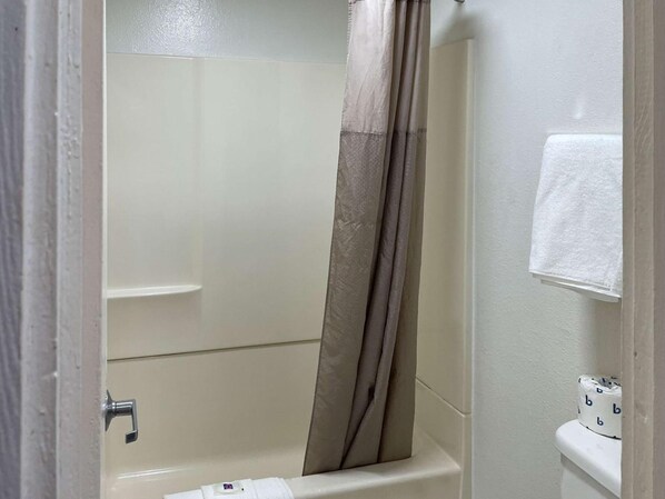 Une salle de bain avec une baignoire, un rideau de douche et des toilettes avec du papier toilette.