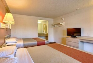 Una habitación de hotel con dos camas, televisión, escritorio y espejo.