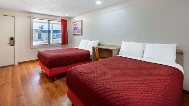 A hotel room with two beds, a desk, a chair, a window with a view of the outside, and a door. - Motel6 Hagerstown, MD (Hagerstown)