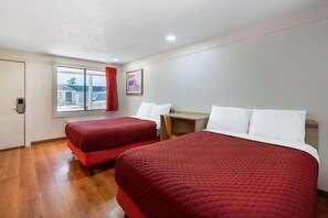 Habitación de hotel con dos camas, un escritorio, una silla, un ventanal con vistas al exterior y una puerta.