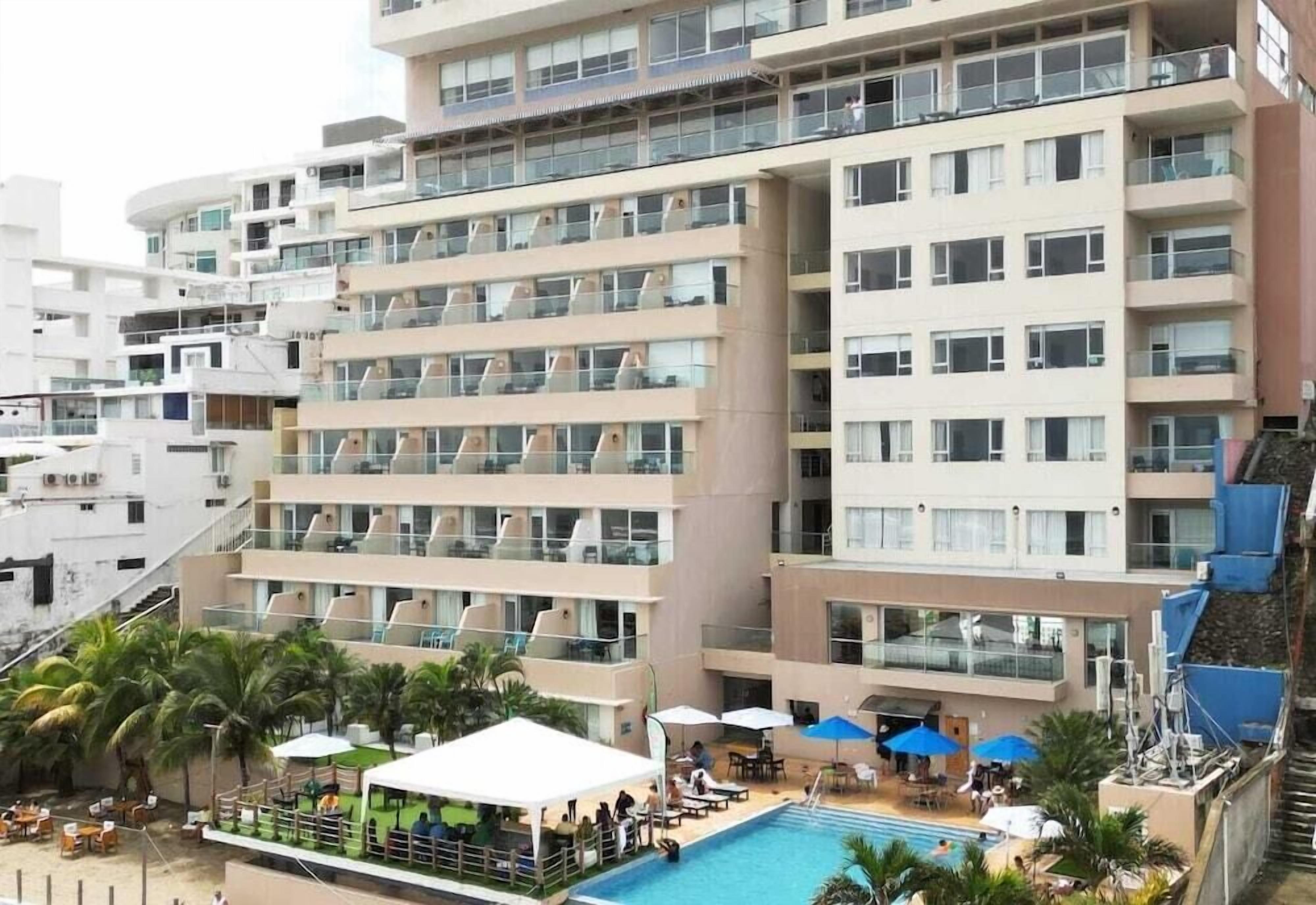Un hotel de varios pisos con balcones, piscina y zona de estar al aire libre.