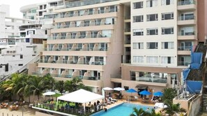 Un hôtel à plusieurs étages doté de balcons, d’un espace piscine et de sièges en plein air.