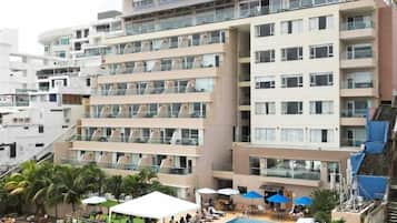 Un hotel de varios pisos con balcones, piscina y zona de estar al aire libre.