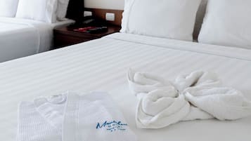 Una habitación de hotel con una cama grande, dos mesitas de noche, un cabecero de madera y una lámpara de pared.
