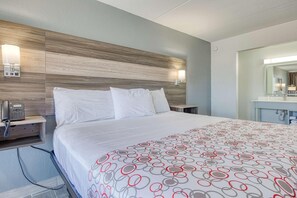A hotel room with a bed, bedside phone, and a bathroom mirror. - OYO Hotel Whitely City Hwy 27 KY (Stearns)