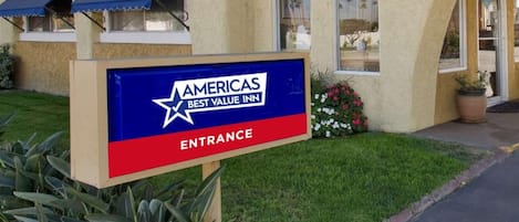 An entrance sign for Americas Best Value Inn with a star logo and the words 'AMERICAS BEST VALUE INN' and 'ENTRANCE' on a blue and red background.