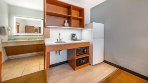 Eine kleine Küche mit einer eingebauten Mikrowelle, einem Kühlschrank und einer Holzausstattung.